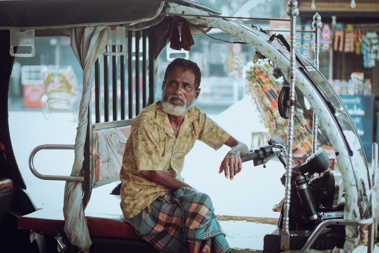 Services Elderly rickshaw driver rests on the streets of Jamalpur, capturing local culture and street life.